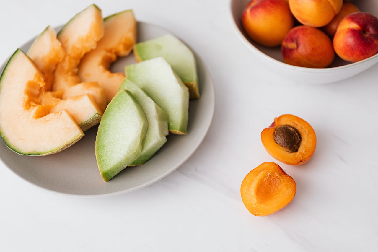 services-02 Flat lay of sliced melon and apricots on a marble background, evoking freshness and healthy eating.